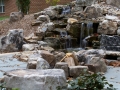 rustic boulder fire pit adjacent to water feature